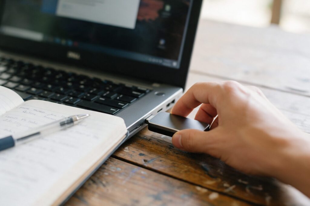 Hand plugging an external hard drive into a laptop to back up business files